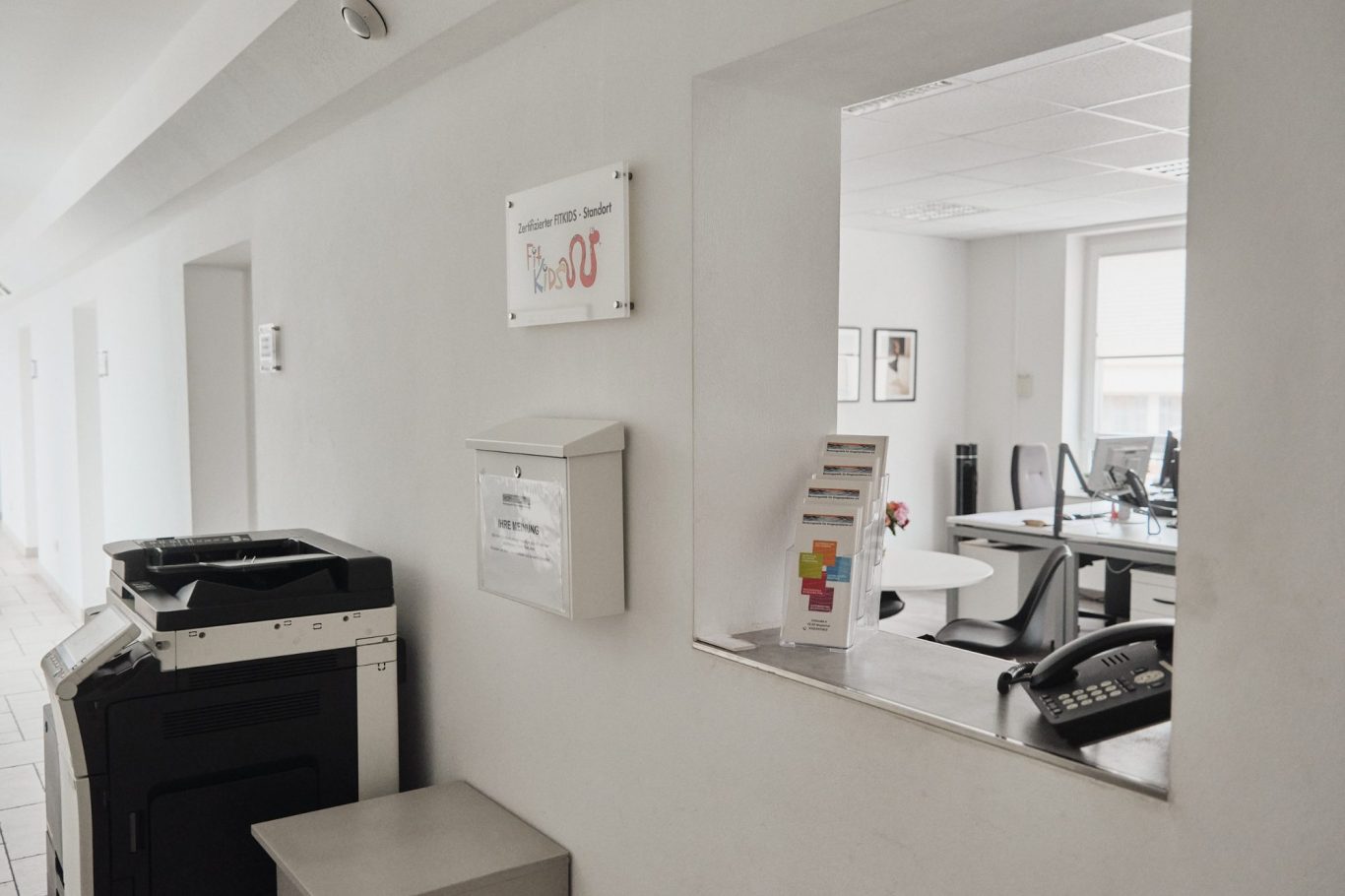 Büro mit Schreibtischen, Stühlen und einem Fenster in einem hellen Raum.