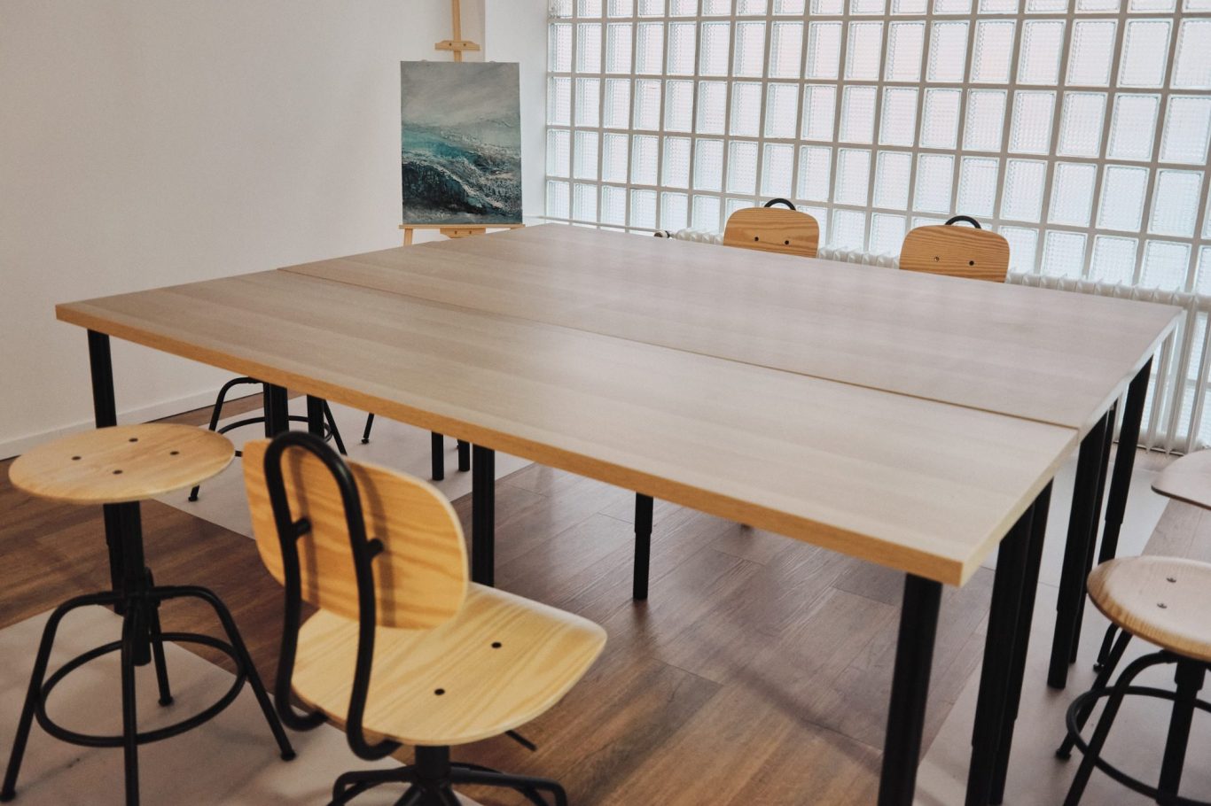 Holztisch mit vier Stühlen in einem modernen Raum, hinter einem farbigen Wandbild.