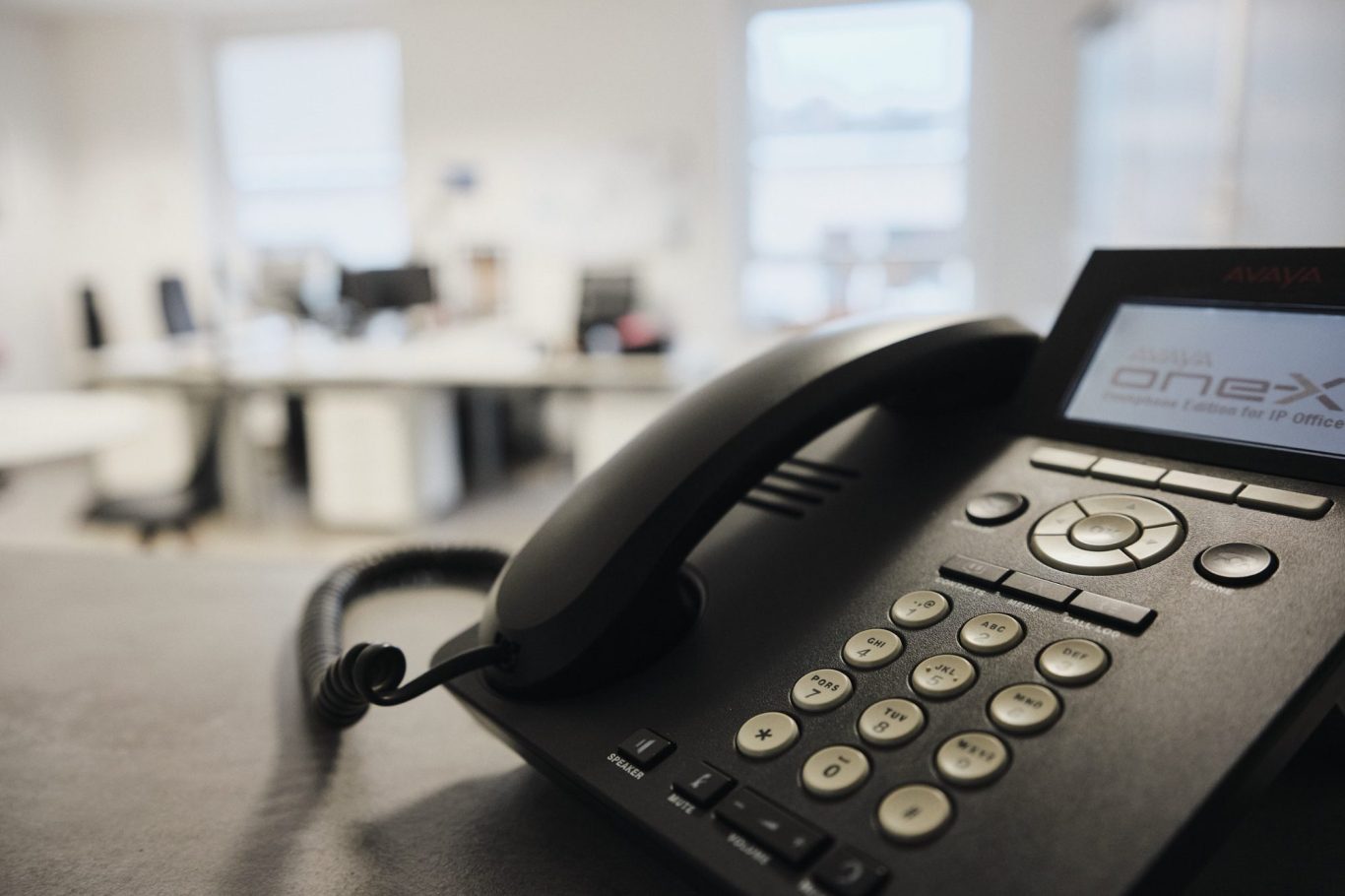 Schwarz telefon auf einem Tisch, mit Büroarbeitsplätzen im Hintergrund.