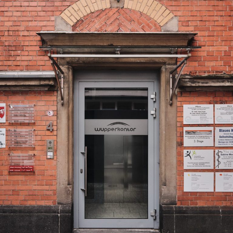 Glas Einnahme von einem Gebäude mit roten Backsteinen und mehreren Informationsschildern.